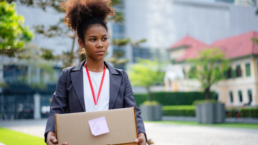 young woman with box of office stuff in business district