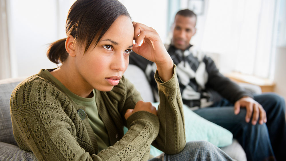 young man and woman sitting on couch having hard conversation