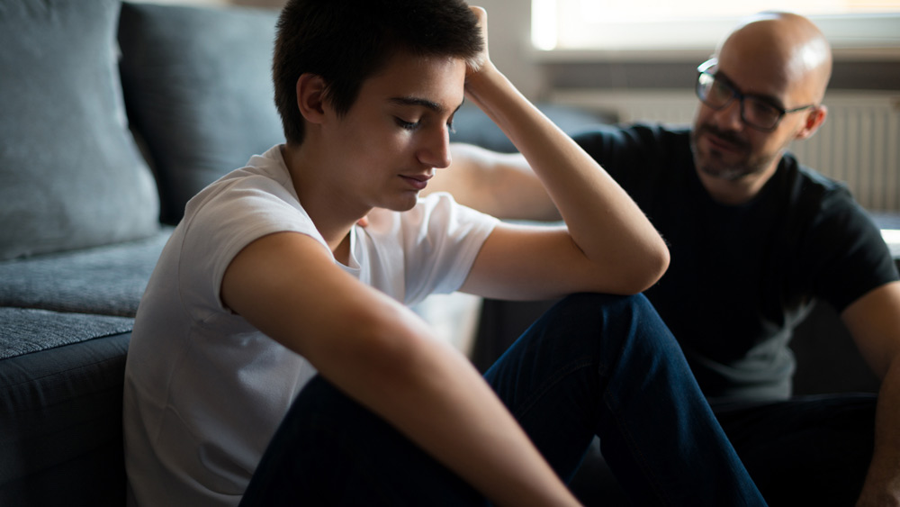 stepfather and son sitting by couch talking