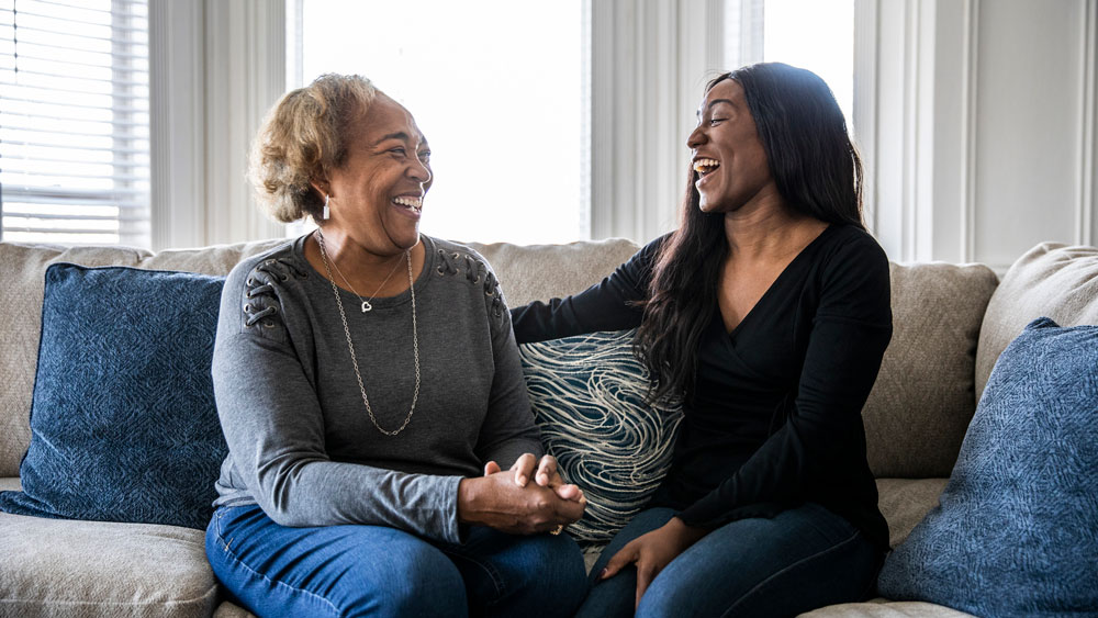 senior mother talking with adult daughter on sofa