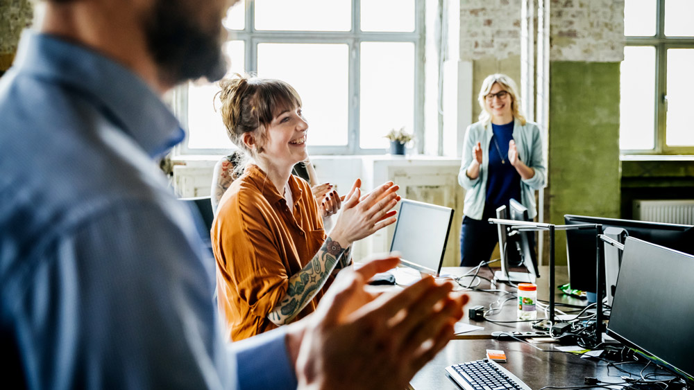 business people applauding to colleague in office