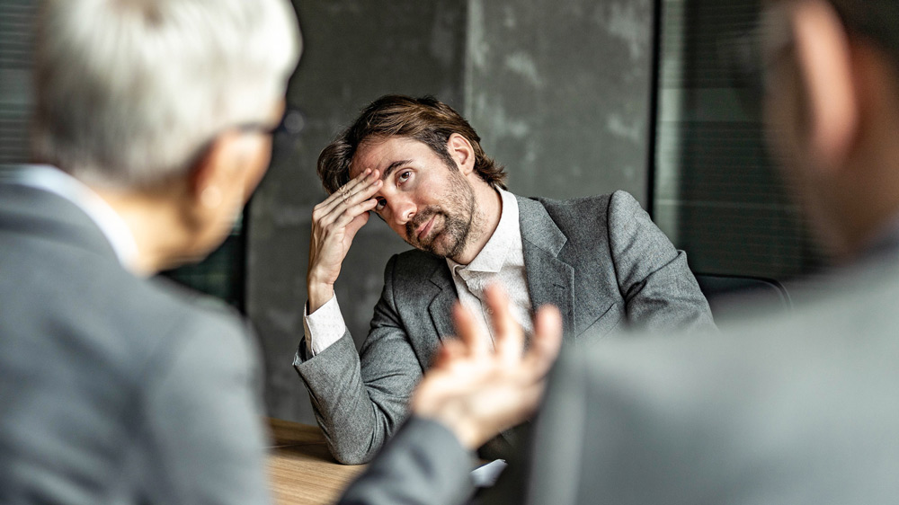 middle-aged office worker looking frustrated with his senior colleague