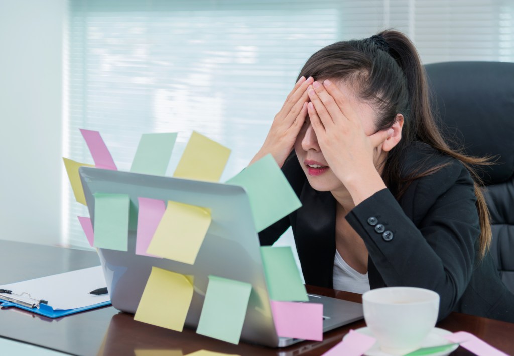 frantic woman sitting at laptop with messy desk