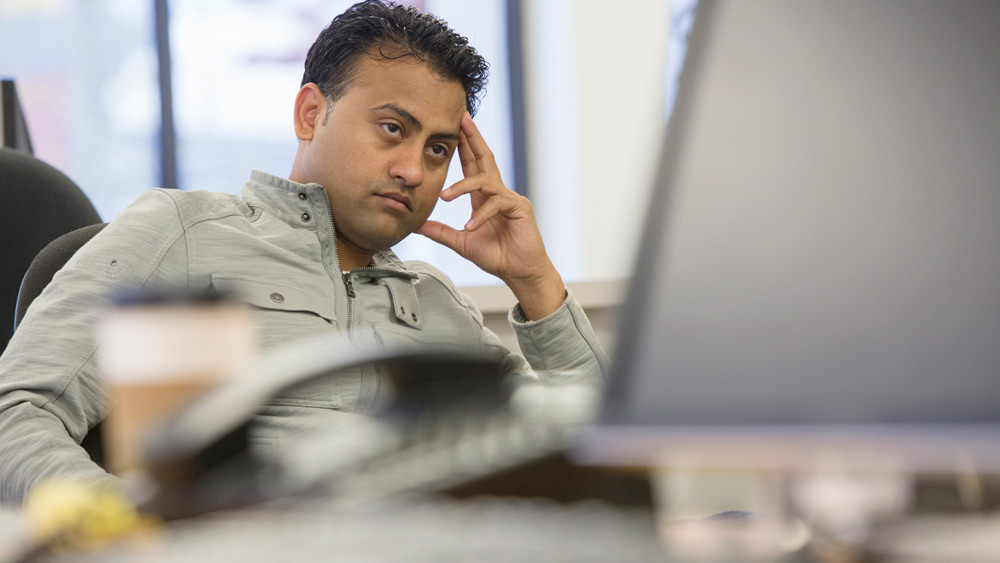 man sitting at desk looking annoyed