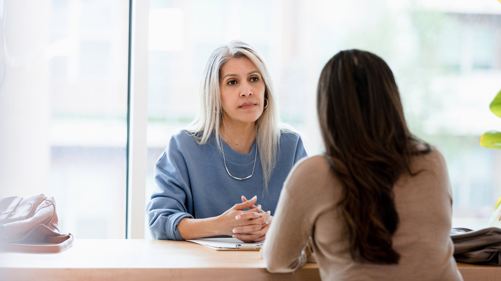 serious businesswoman listens to female direct report