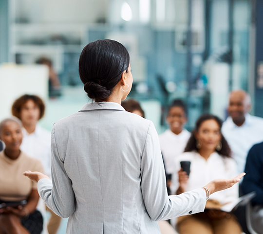 a woman training a large group in a professional business environment