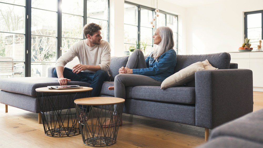 mother and adult son sitting on couch talking