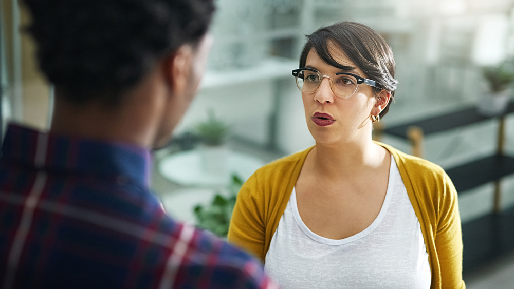 woman and man in office talking looking defensive