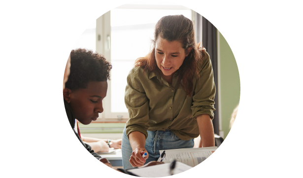 Teacher assisting two students at a table